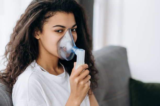 生病的非裔美国妇女与吸入器的特写照片。不健康的千禧女孩在家里做吸入，她使用喷雾器和吸入器治疗。咳嗽和感冒图片下载