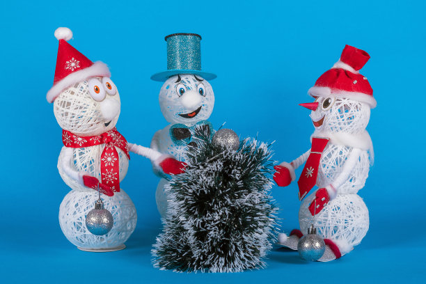 新年历险，三个雪人围绕着一棵蓝色背景的喜庆的冷杉树图片下载