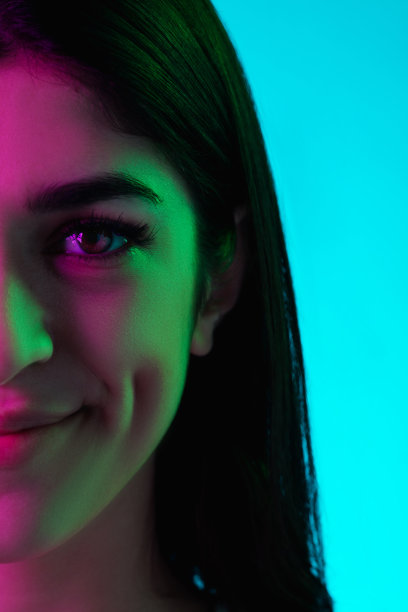 黑发美人的肖像孤立在彩色霓虹灯的蓝色工作室背景图片下载