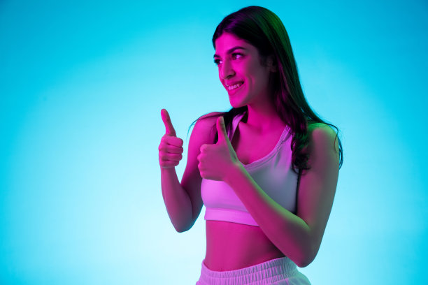 黑发美人的肖像孤立在彩色霓虹灯的蓝色工作室背景图片下载