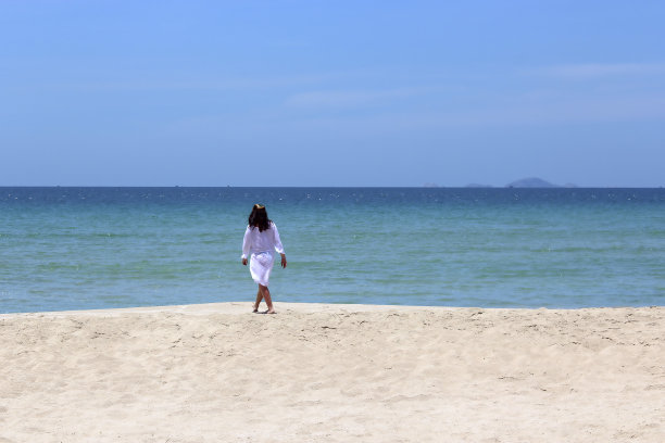 女孩背对着大海，站在沙滩上图片下载