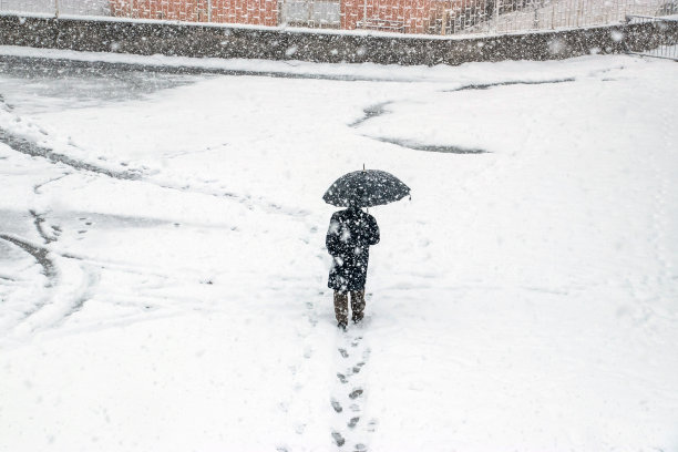 一个男人在大雪中撑着伞走图片下载