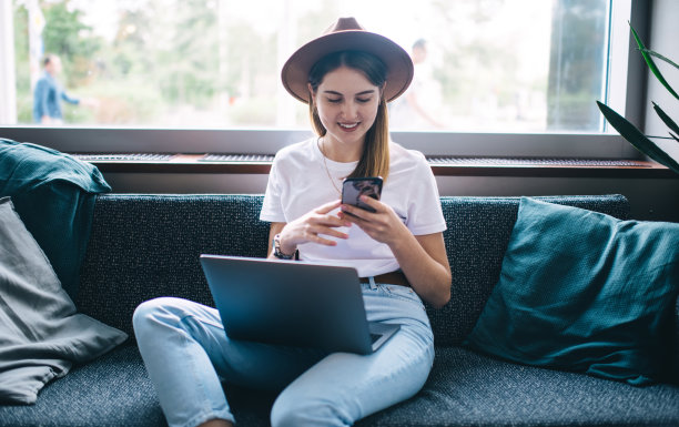 富裕的白人女性自由职业者满意的在线项目资金收入在智能手机上检查银行应用程序通知，快乐的嬉皮士女孩确认交易在手提电脑上的蜂窝工作图片下载