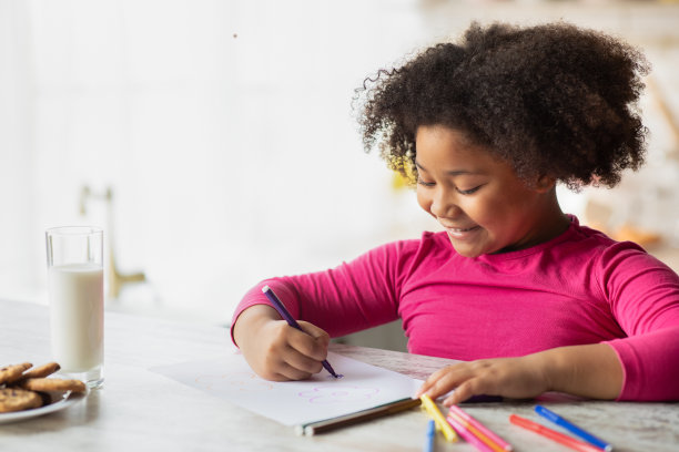 幼儿园的活动。可爱的小黑人女孩在厨房用彩色铅笔画画图片下载