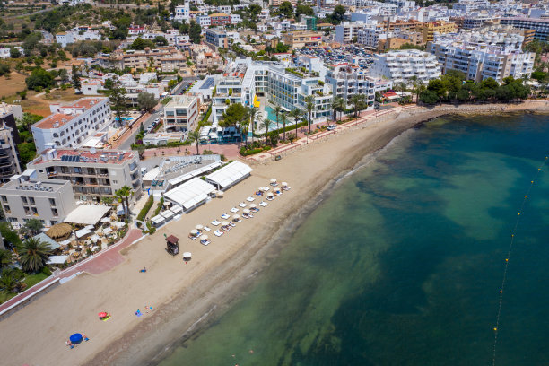 这是西班牙伊比沙岛美丽的无人机拍摄的照片，在一个炎热阳光明媚的夏日，海边金色的沙滩上，人们在放松和日光浴图片下载