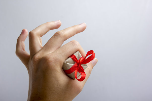 在灰色背景下，女性手握礼品盒。快乐的家庭庆祝概念为情人节，生日，圣诞节或新年图片下载