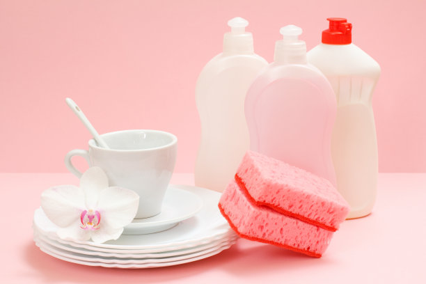 粉红色背景上的洗洁精和餐具。图片下载