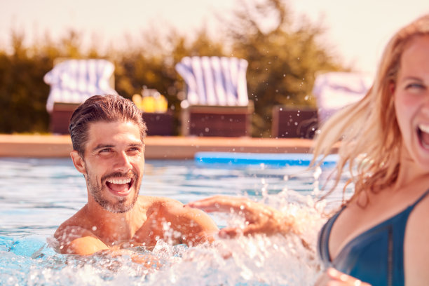 夫妇有乐趣在夏季假期在室外游泳池溅水图片下载