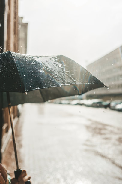 傍晚的雨和黑色的雨伞映衬着一个废弃的城市街道。特写视图。图片下载