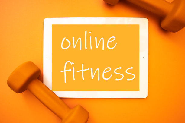 橙色背景下的哑铃平板电脑。在隔离健康生活方式的概念下，找家有在线培训师。图片下载