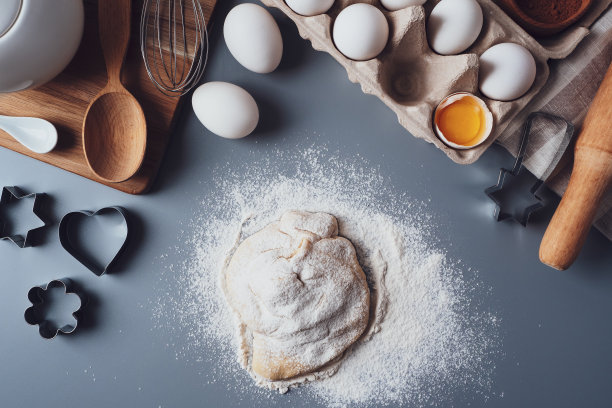 女孩用木擀面杖擀出面团，用来做纸杯蛋糕或饼干。平面构图用厨具和食材，复制空间。节日烘焙的概念图片下载