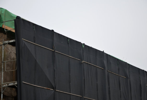 街上一所修理过的房子的脚手架。在人行道上覆盖着一个绿色的塑料布网，以防止跌落的物体和工具。防止行人和车辆受伤图片下载