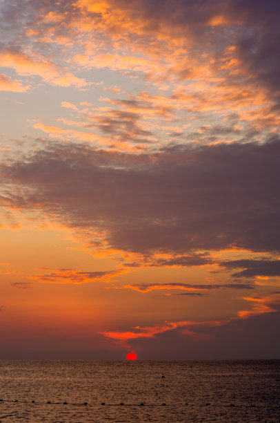 卵石滩上惊人的海上日落，太阳，海浪，云彩图片下载