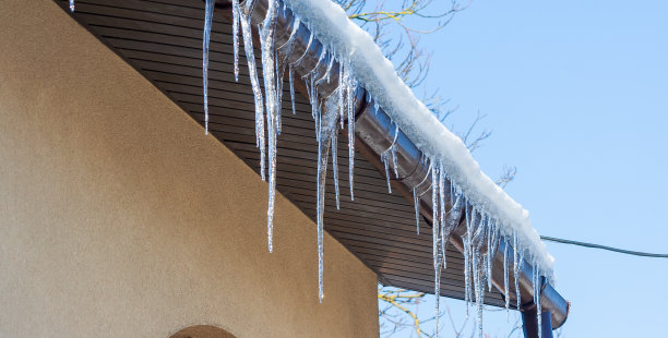 屋顶上挂着又长又危险的冰柱。冬季的概念。霜雪天气图片下载