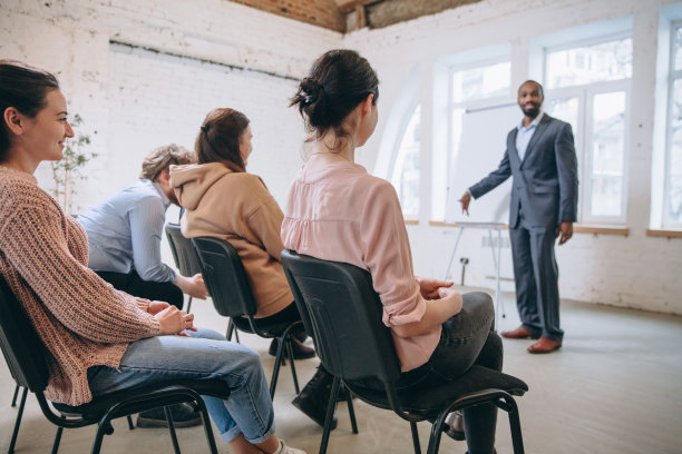 男演讲人在车间大厅演讲。观众或会议厅。未被认可的参与者的侧视图。图片下载