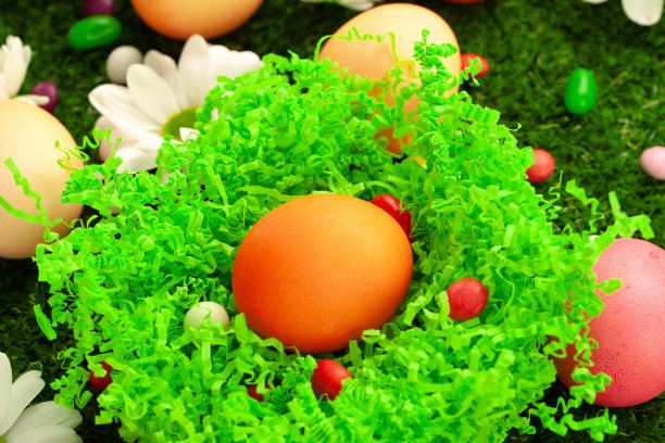 近距离的彩色复活节彩蛋和糖果在草地上的照片图片下载