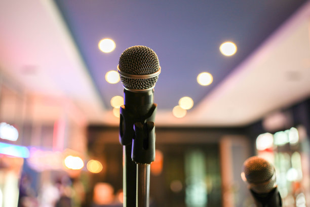 近距离的黑色麦克风站在音乐厅舞台上的背景为娱乐表演活动的概念图片下载