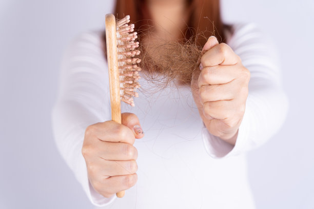 头发掉落问题，近距离握梳子和问题头发。医疗保健或日常生活概念。图片下载