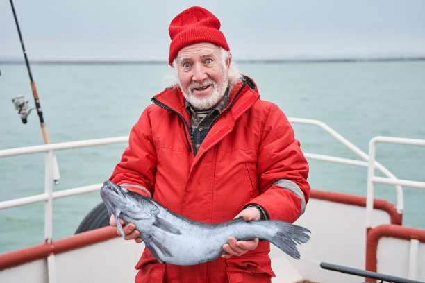 渔夫站在甲板上展示他的捕获物图片下载