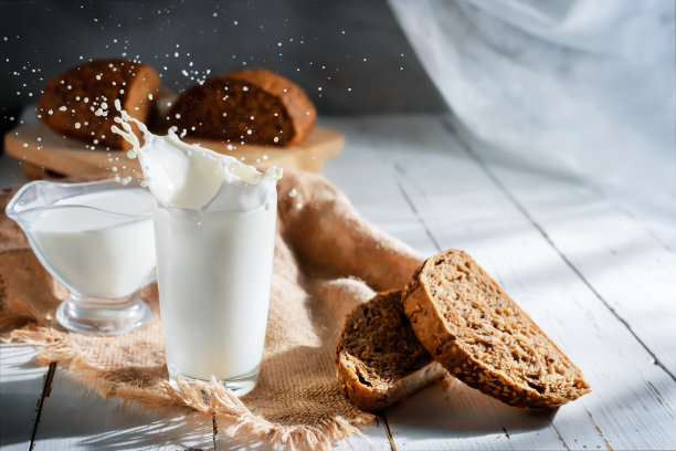 洒在玻璃杯里的牛奶和全麦面包图片下载