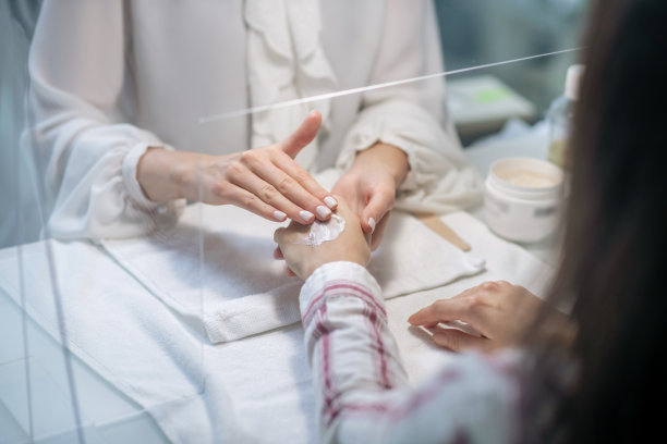 近距离的图片，美容师的手在客户的手上涂抹霜图片下载