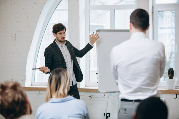 男演讲人在车间大厅演讲。观众或会议厅。未被认出的参与者的后视图。图片下载