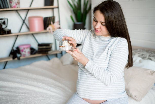 饥饿的孕妇吃不健康的食物——蛋糕。孕期对甜食的渴望。图片下载