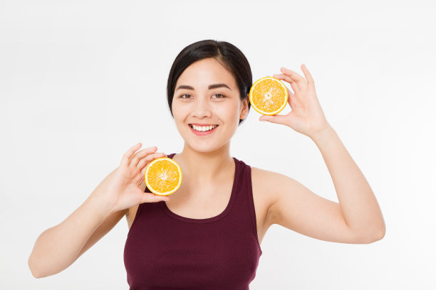 美丽的亚洲日本女人拿着橘子。美丽的概念。美丽快乐的少女与雀斑，有趣的红色发型和黄色的化妆。橙片图片下载