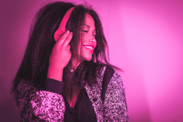 一个年轻快乐的西班牙女性戴着紫色耳机欣赏音乐的特写图片下载
