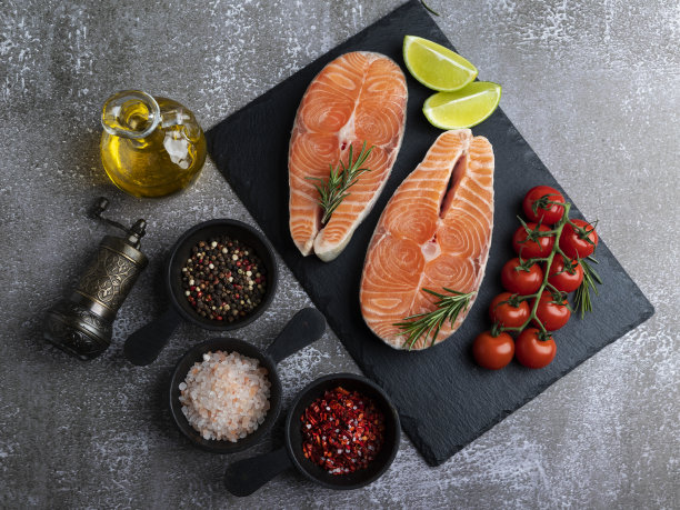 两条生鲜鳟鱼、鲑鱼和香料排在黑色石面上，深色背景，俯视图片下载