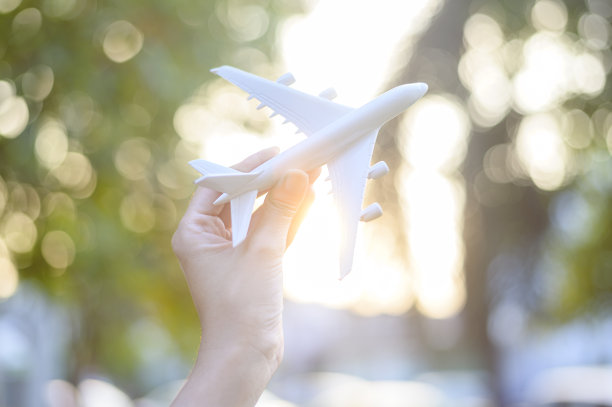 女人手握飞机模型，迎着夕阳，度假旅游，商务节约交通理念。图片下载