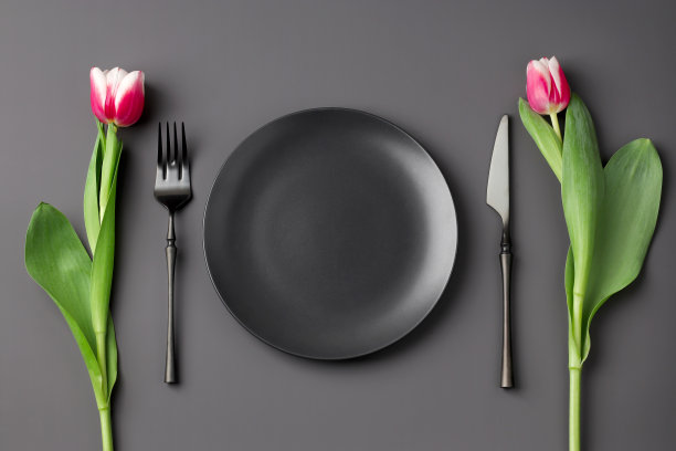 节日创意黑色餐桌设置与郁金香花束在黑暗的背景。情人节，婚礼，生日，妇女节和母亲节。平的。图片下载