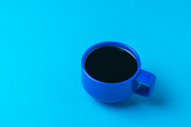 蓝色背景下的一杯黑咖啡。图片下载