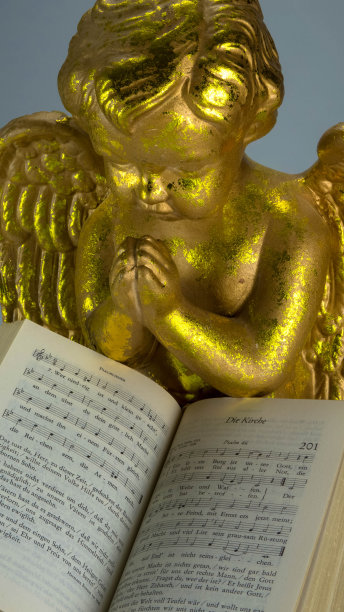 一个金色天使的肖像，在打开的旧圣经后面祈祷。地域与悼念概念。图片下载