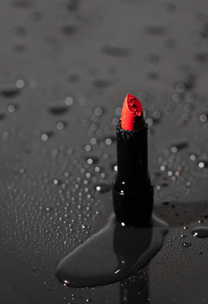 近距离的红色饱和唇膏与水滴。装饰性化妆品。面部和脸部化妆图片下载