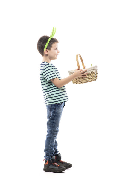 侧视图的快乐男孩分发篮子里装满了复活节彩蛋寻找。图片下载
