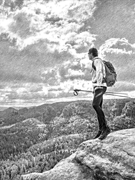 一个背着背包的游客在岩石山顶上。男人拿着登山杖。图片下载