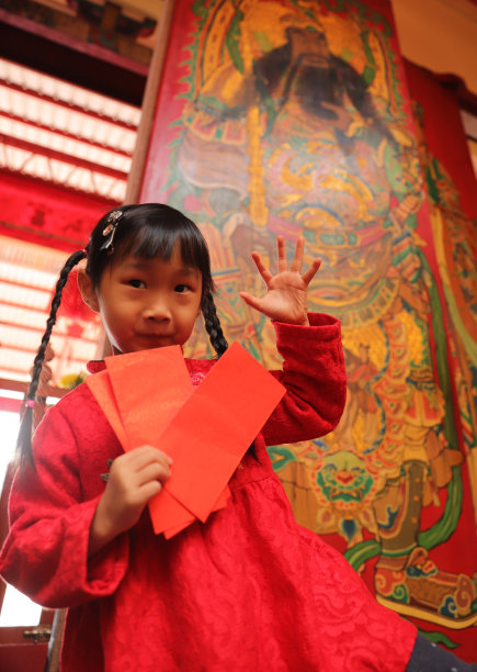 两个亚洲双胞胎女孩穿着旗袍在寺庙前进行新年访问。图片下载