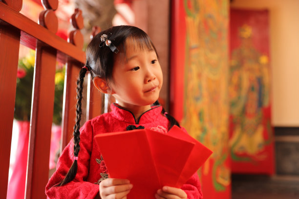 两个亚洲双胞胎女孩穿着旗袍在寺庙前进行新年访问。图片下载