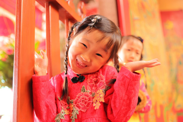 两个亚洲双胞胎女孩穿着旗袍在寺庙前进行新年访问。图片下载