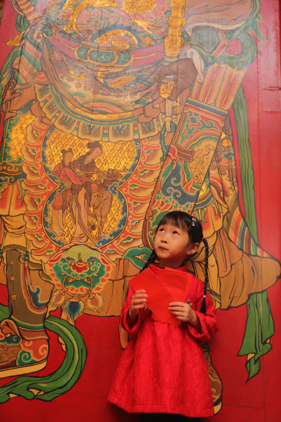 两个亚洲双胞胎女孩穿着旗袍在寺庙前进行新年访问。图片下载