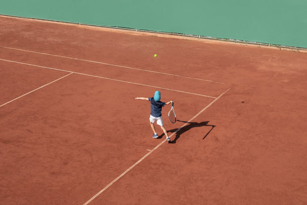 儿童网球运动概念。儿童网球运动员在红土球场发球。运动中的男孩运动员。从上面俯视，背景，复制空间图片下载