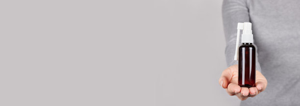 手拿医用喉喷雾剂，涂在灰色背景上。图片下载