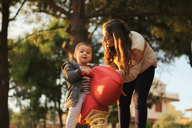 快乐的小男孩和他的妹妹玩跷跷板。图片下载