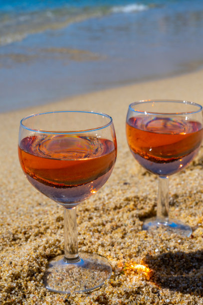 两杯当地的玫瑰葡萄酒在白色的沙滩和蓝色的地中海背景，靠近勒Lavandou，法国普罗旺斯图片下载