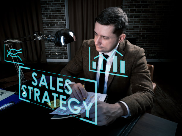 销售策略信息概念。男人在桌边工作到很晚。图片下载