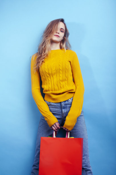 年轻漂亮的女人摆情绪与蓝色背景袋，生活方式的人概念图片下载