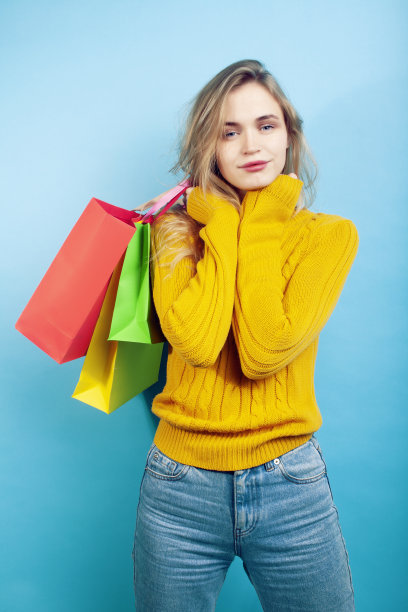 年轻漂亮的女人摆出情绪化的蓝色背景与包，生活方式的人概念特写图片下载