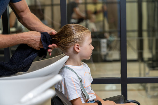 一个男孩在美发师的头上洗完澡后用毛巾擦干图片下载