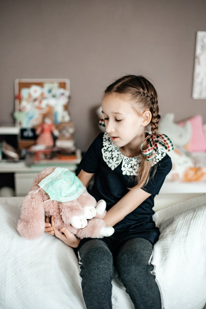 这个孩子手里拿着一个带医用口罩的玩具。图片下载